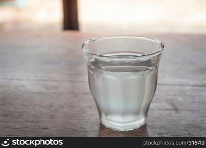 Drinking water in a glass on wooden table, stock photo