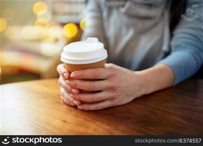 drinks and people concept - close up of young woman with paper coffee cup over festive lights background. close up of young woman with paper coffee cup