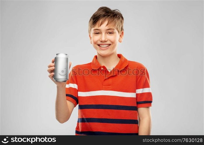 drinks and people concept - happy smiling boy in red polo t-shirt holding soda drink in tin can over grey background. happy smiling boy holding soda drink in tin can