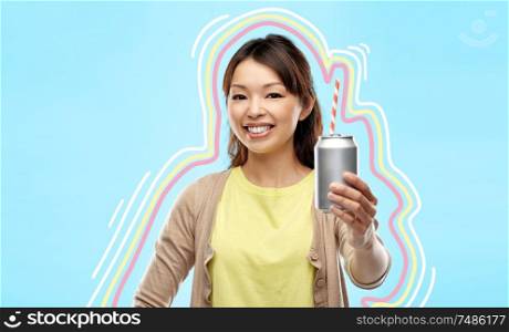 drinks and people concept - happy young asian woman drinking soda from can with paper straw over blue background with glowing lines. happy asian woman with can drink