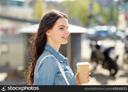 drinks and people concept - happy young woman or teenage girl drinking coffee from paper cup on city street. happy young woman drinking coffee on city street