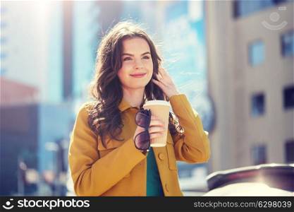 drinks and people concept - happy young woman or teenage girl drinking coffee from paper cup on city street. happy young woman drinking coffee on city street. happy young woman drinking coffee on city street