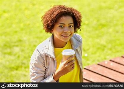 drinks and people concept - smiling african american young woman or teenage girl drinking coffee from paper cup outdoors. smiling african woman drinking coffee outdoors