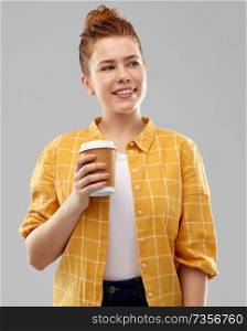 drinks and people concept - smiling red haired teenage girl in checkered shirt with takeaway coffee cup over grey background. happy redhead teenage girl with paper coffee cup