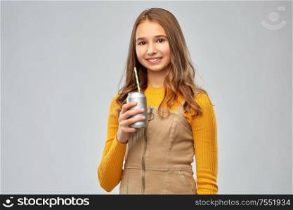 drinks and people concept - smiling teenage girl drinking soda from can with paper straw over grey background. happy teenage girl drinking soda from can