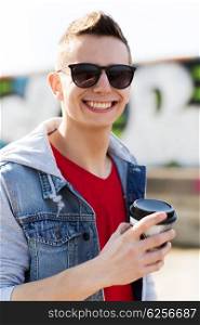 drinks and people concept - smiling young man or teenage boy drinking coffee from paper cup outdoors. smiling young man or boy drinking coffee