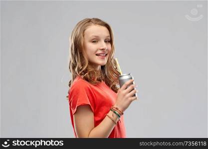 drinks and people concept - teenage girl in red t-shirt drinking soda from can through paper straw over grey background. girl drinking soda from can through paper straw