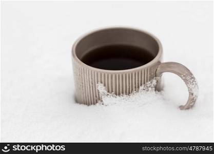 drinks, christmas and winter holidays concept - tea or coffee mug in snow