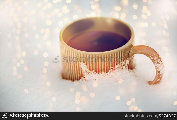 drinks, christmas and winter holidays concept - tea or coffee mug in snow. tea or coffee mug in snow
