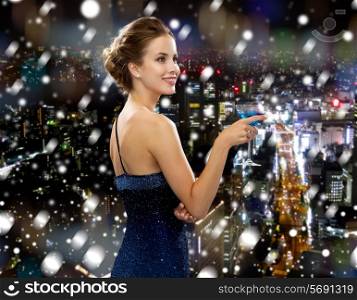 drinks, christmas, holidays and people concept - smiling woman in evening dress holding cocktail over snowy night city background