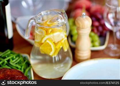 drinks concept - glass jug of lemon water and food on table. glass jug of lemon water and food on table
