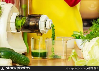 Drinks good for health, diet breakfast concept. Woman in kitchen making green healthy vegetable smoothie juice from green vegetables. Woman in kitchen making vegetable smoothie juice