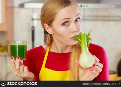 Drinks good for health, diet breakfast concept. Young woman in kitchen holding green healthy vegetable fennel smoothie juice glass. Woman in kitchen holding vegetable fennel smoothie juice