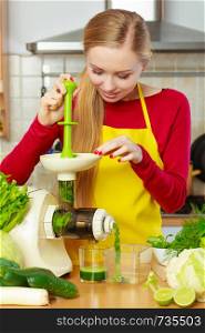 Drinks good for health, diet breakfast concept. Young woman in kitchen making green healthy vegetable smoothie juice from green vegetables. Woman in kitchen making vegetable smoothie juice