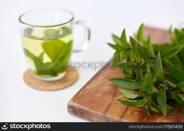 drinks, herbs and ethnoscience concept - herbal tea with fresh peppermint on wooden board. herbal tea with fresh peppermint on wooden board