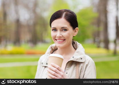 drinks, leisure and people concept - smiling woman drinking coffee in park