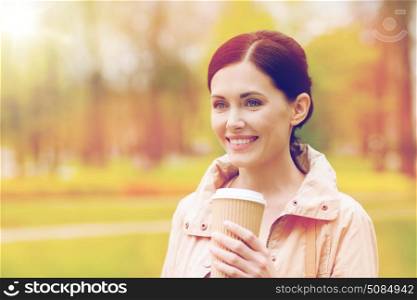 drinks, leisure and people concept - smiling woman drinking coffee in park. smiling woman drinking coffee in park. smiling woman drinking coffee in park