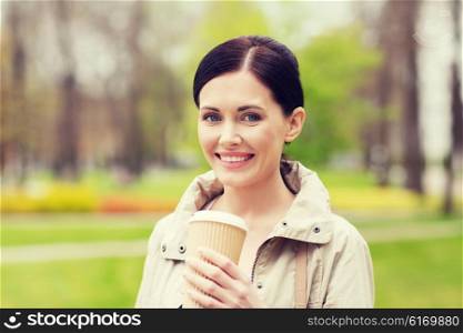 drinks, leisure and people concept - smiling woman drinking coffee in park
