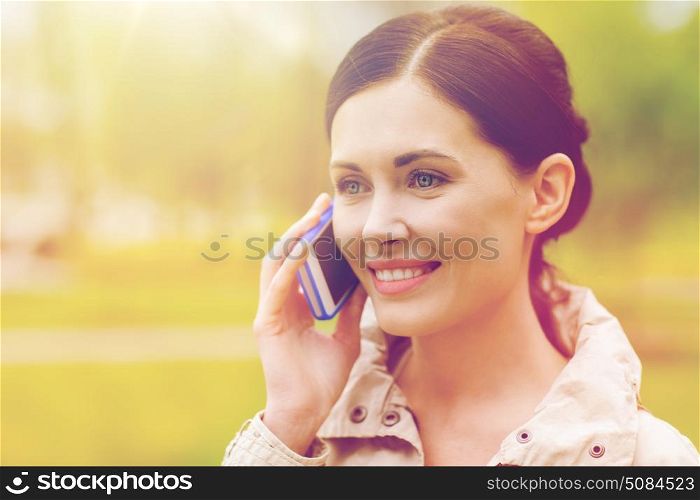 drinks, leisure, technology and people concept - smiling woman calling and talking on smartphone in park. smiling woman calling on smartphone in park. smiling woman calling on smartphone in park