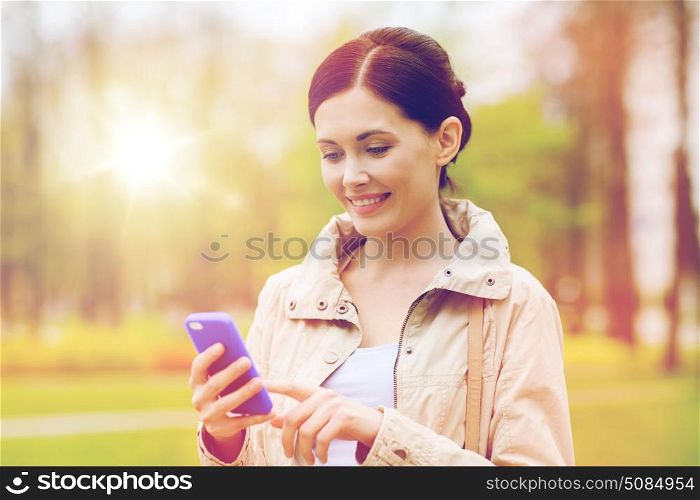 drinks, leisure, technology and people concept - smiling woman calling and talking on smartphone in park. smiling woman calling on smartphone in park. smiling woman calling on smartphone in park