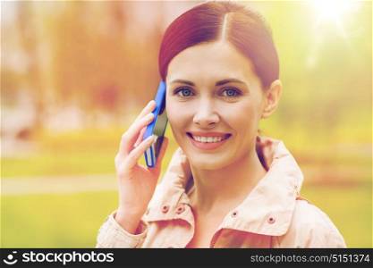 drinks, leisure, technology and people concept - smiling woman calling and talking on smartphone in park. smiling woman calling on smartphone in park