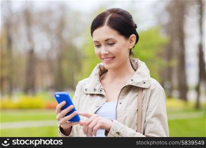 drinks, leisure, technology and people concept - smiling woman calling and talking on smartphone in park