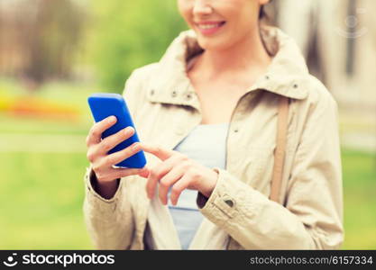 drinks, leisure, technology and people concept - smiling woman calling or texting message on smartphone in park