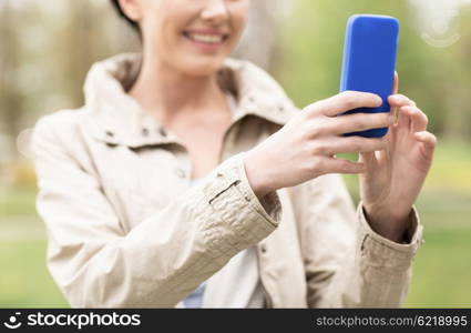 drinks, leisure, technology and people concept - smiling woman taking picture or selfie with smartphone in park