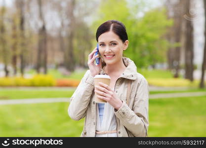 drinks, leisure, technology and people concept - smiling woman with coffee calling and talking on smartphone in park