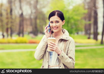 drinks, leisure, technology and people concept - smiling woman with coffee calling and talking on smartphone in park