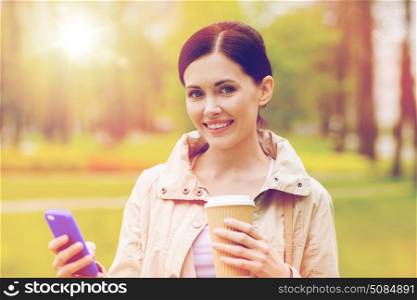 drinks, leisure, technology and people concept - smiling woman with smartphone and coffee in park. smiling woman with smartphone and coffee in park. smiling woman with smartphone and coffee in park