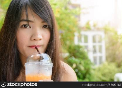 Drinks, people and lifestyle concept - close up of woman drinking ice tea from plastic cup with straw at cafe