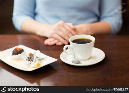 drinks, people and lifestyle concept - close up of woman hands with coffee cup and dessert