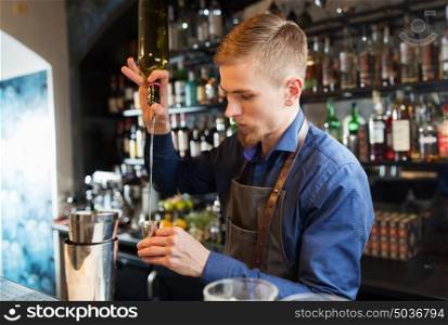 drinks, people and luxury concept - barman with shaker pouring alcohol from bottle into jigger and preparing cocktail at bar. barman with shaker preparing cocktail at bar