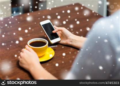 drinks, people, technology and communication concept - young woman with smartphone drinking coffee at cafe over snow