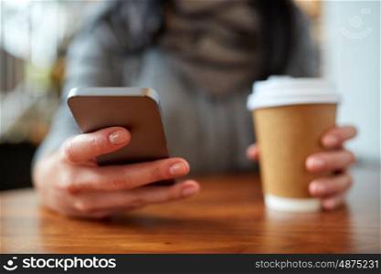 drinks, people, technology and lifestyle concept - close up of woman with smartphone and coffee at cafe table