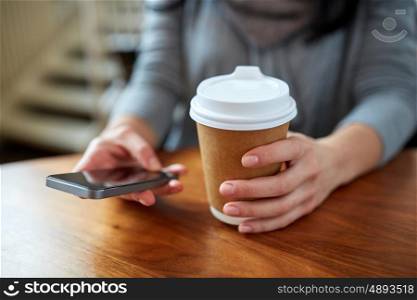 drinks, people, technology and lifestyle concept - close up of woman with smartphone and coffee at cafe table