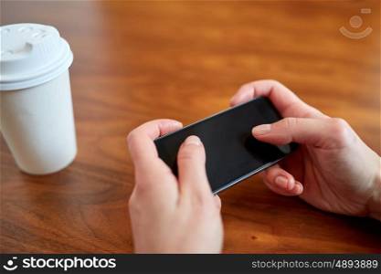 drinks, people, technology and lifestyle concept - close up of woman with smartphone and coffee at table