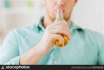 drinks, relax, leisure and people concept - close up of man drinking beer sitting on couch at home
