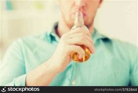 drinks, relax, leisure and people concept - close up of man drinking beer sitting on couch at home