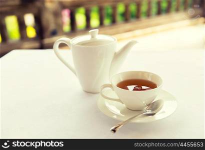 drinks, relaxation and tea party concept - tea-set of cup, pot, spoon and saucer at teahouse