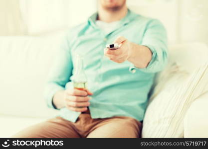 drinks, television, leisure and people concept - man changing tv channels and drinking beer at home