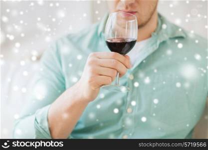 drinks, winery, leisure and people concept - close up of man with glass drinking red wine at home
