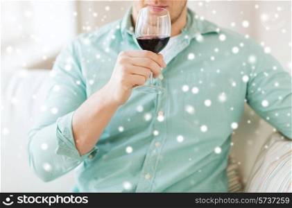 drinks, winery, leisure and people concept - close up of man with glass drinking red wine at home