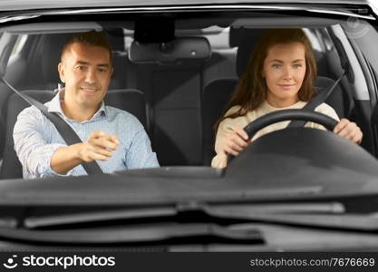 driver courses and people concept - car driving school instructor teaching young woman to drive. car driving school instructor teaching woman