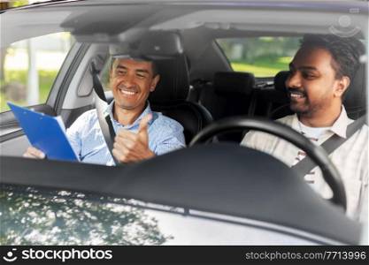 driver courses, exam and people concept - happy smiling indian man and driving school instructor with clipboard showing thumbs up in car. smiling car driving school instructor and driver