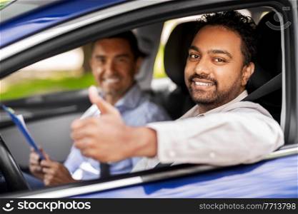 driver courses, exam and people concept - happy smiling indian man showing thumbs up and driving school instructor with clipboard in car. smiling driver and car driving school instructor