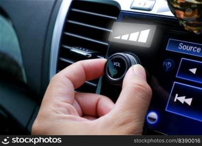 Driver hand adjust volume control on the car radio dashboard