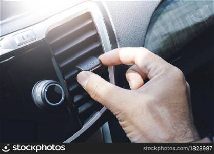 Driver hand adjusting wind direction of air vent on console in the car