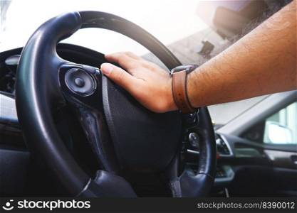 Driver hand pressing on steering wheel honking horn